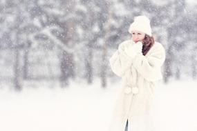 photo of a woman in a white fur coat in snowfall