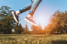 Legs of the jumping person, among the colorful and beautiful pants, at colorful sunlight in the sky