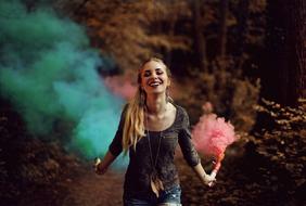 Happy young girl runs with Colourful smoke in hands
