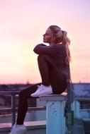 sporty Woman sits on bench at Sunset