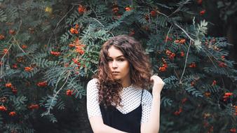 Beautiful bright girl near the bushes with the berries