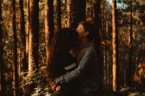 Couple, hugging, among the colorful and beautiful trees, in the forest, in sunlight