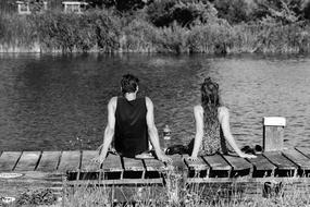 black and white photo of a couple in love on a wooden pier