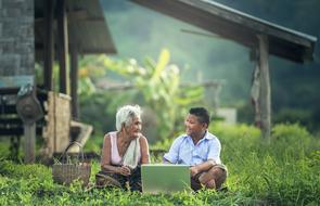 Grandmother with the son, among the green plants, in sunlight, in Myanmar