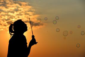 woman blowing bubbles at sunset