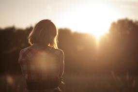 Back view of the woman, standing near the plants, in the beautiful sunset, on the landscape
