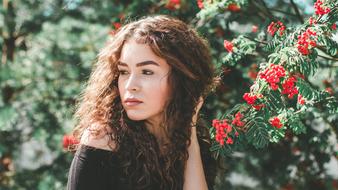 beautiful girl near a bush with red flowers