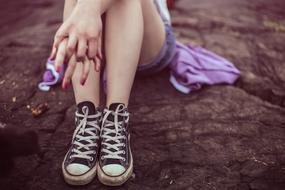 girl in sneakers sitting on the ground