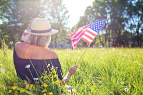 girl with american flag on green meadow