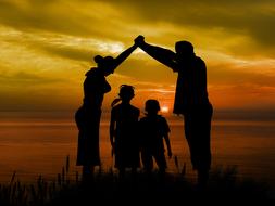 silhouette of family on the beach at dusk