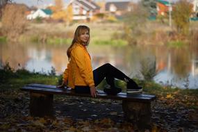 pretty blonde girl sits on Bench in Park at fall