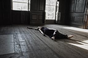 woman lying on the floor of an abandoned house
