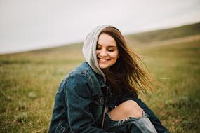 happy girl in denim jacket on the field in the wind