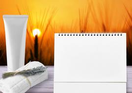 notebook, cream and towel on sunset background