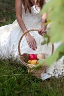 bride with a basket of fruit on a green meadow