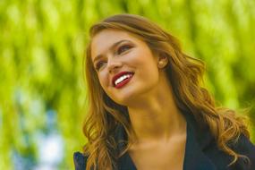 Portrait of the smiling girl with red lips, posing among the beautiful, green and yellow plants