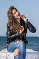 happy Beautiful Girl sits on stone at sea