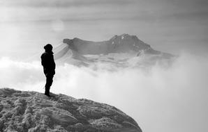 black and white photo of a girl on a rock in the clouds