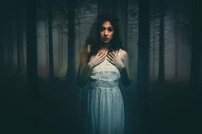 Portrait of the beautiful woman in white dress, among the foggy forest