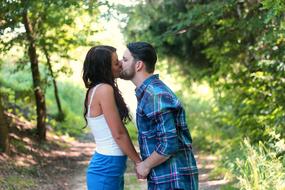 kiss of a couple in love on a forest trail