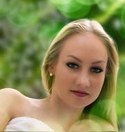 Portrait of the blonde, smiling girl with make-up, among the green plants