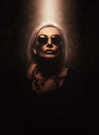 Woman in sunglasses with light on her on dark background