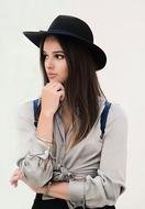 photo of a brunette with a black hat on a white wall background