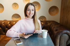 Girl with the tablet and phone in the cafe