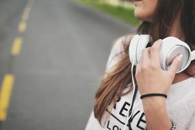 Girl with white headphones, among the road