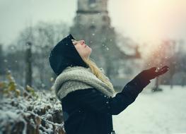 girl in a black jacket with a scarf under the snow