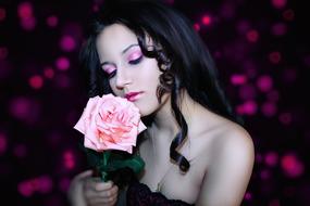 Portrait of the beautiful, girl, with the make-up and beautiful, pink and orange flower, at blurred background