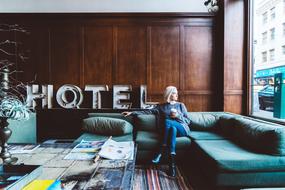 Woman with white hair, sitting on the beautiful sofa, in the room with "HOTEL" sign