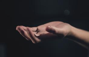 Person's hand with open palm, at black background