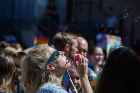 Blonde woman with glasses, blowing bubbles on the colorful party