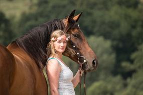 photo of a girl with a floral wreath and a brown horse