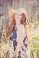 Beautiful happy redhead girl in wide hat at Summer