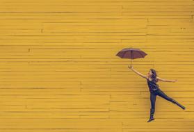 girl with umbrella on the background of a yellow wooden wall