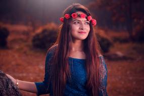 beautiful girl in a red wreath posing in the forest