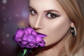 portrait of a beautiful girl with a bright purple flower on a blurred background