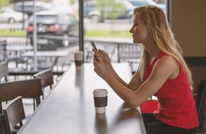 woman sitting in cafe with phone