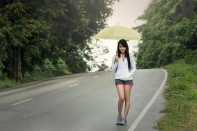 young woman on the road under umbrella