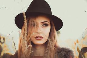 fashionable girl in a black hat on a cereal field
