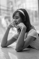 Black and white photo of the beautiful, smiling girl, sitting at the table