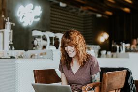 smiling woman with laptop in cafe