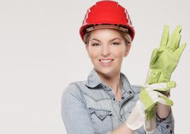 beautiful girl in a red helmet and construction gloves