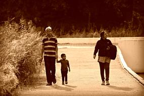 senior man with child boy and woman walking on path