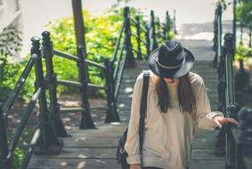 girl in a black hat climbs the stairs in the park