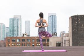 girl is doing stretching on the roof of the building
