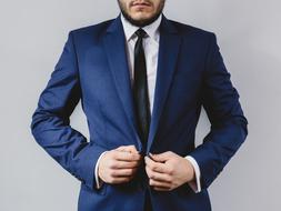 Bearded man in blue suit, white shirt and black tie