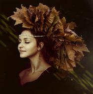 Profile portrait of a woman, with the beautiful and colorful leaves and beads, in the autumn